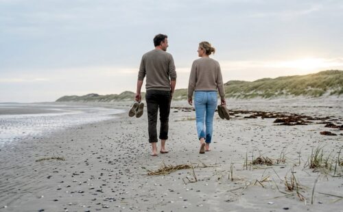 Op het uitgestrekte, verlaten strand van Ameland genieten wandelaars in alle rust van een ontspannen wandeling.