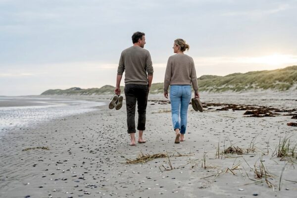 Op het uitgestrekte, verlaten strand van Ameland genieten wandelaars in alle rust van een ontspannen wandeling.
