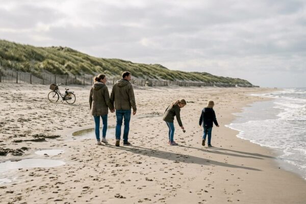 Gezin maakt een ontspannen wandeling langs het strand van de Waddeneilanden.