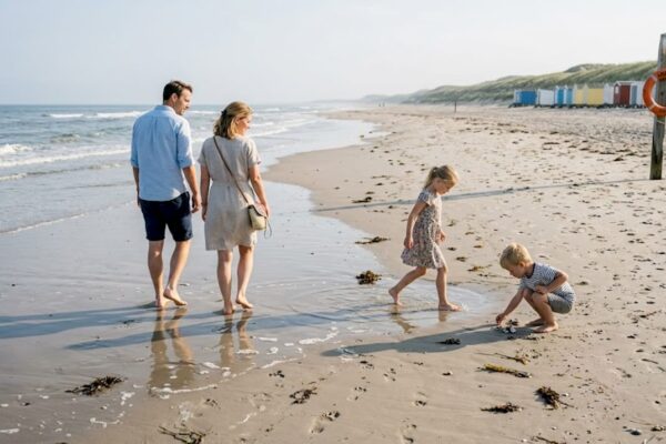 Een gezin wandelt samen over het uitgestrekte, rustige strand.
