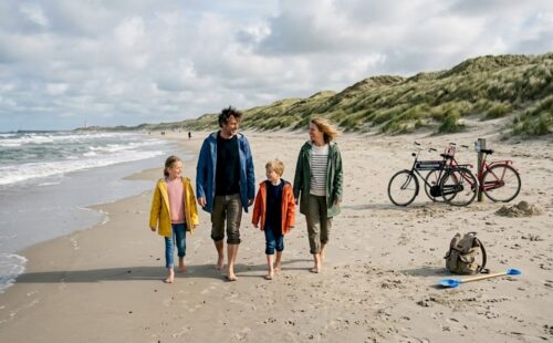 Een gezin maakt een ontspannen wandeling langs het strand op een Waddeneiland.