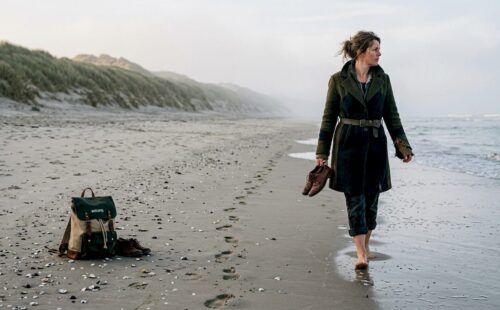 Vrouw geniet in alle rust van haar ochtendwandeling over het verlaten strand van Ameland