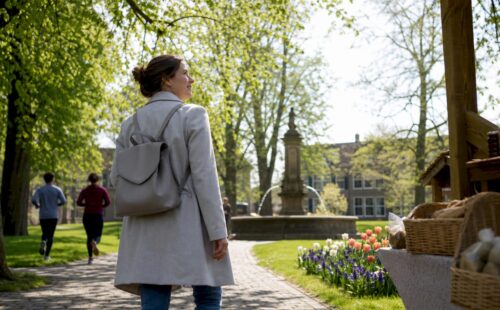 Een vrouw slentert op haar gemak over het dorpsplein en geniet van de lokale sfeer en tradities.