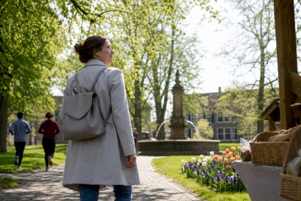 Een vrouw slentert op haar gemak over het dorpsplein en geniet van de lokale sfeer en tradities.