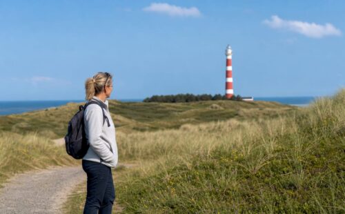 Wandelaars genieten van het strand bij de vuurtoren van Ameland
