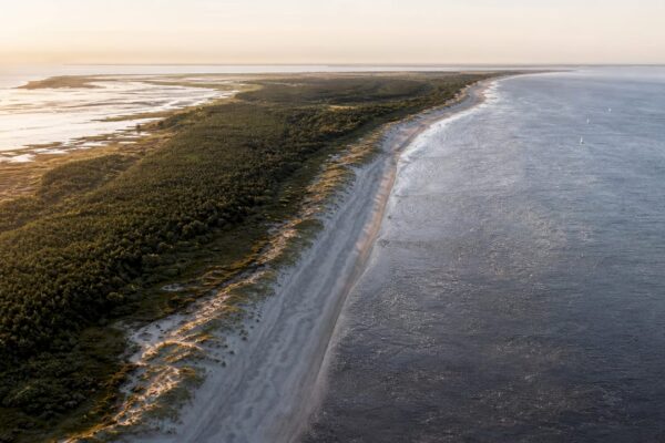 Een prachtige luchtfoto van Ameland, waarop de uitgestrekte kustlijn en het unieke landschap van het eiland goed zichtbaar zijn.
