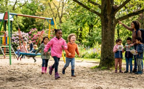 Een groepje kinderen loopt samen met een volwassene over een bospad.