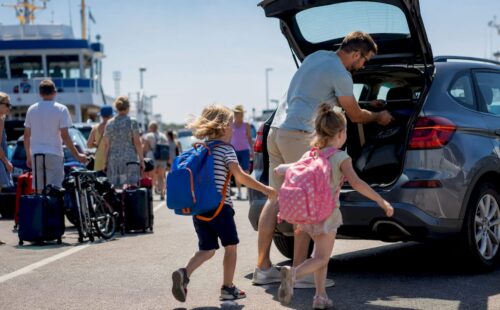Een gezin is druk bezig met het inladen van koffers bij de veerboot naar de Waddeneilanden.