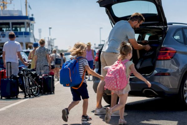 Een gezin is druk bezig met het inladen van koffers bij de veerboot naar de Waddeneilanden.