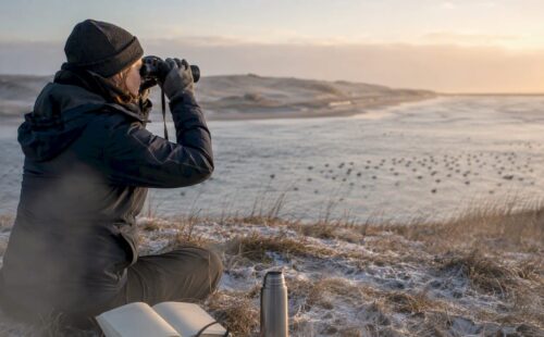 Een vrijwilliger stelt de telescoop scherp langs de kust van Ameland.