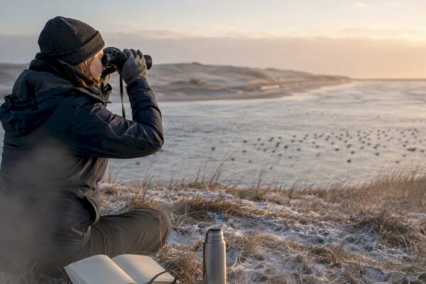 Een vrijwilliger stelt de telescoop scherp langs de kust van Ameland.