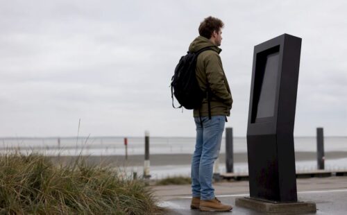 Een reiziger kijkt bij de veerbootterminal op het bord om te zien hoe laat de volgende boot vertrekt.