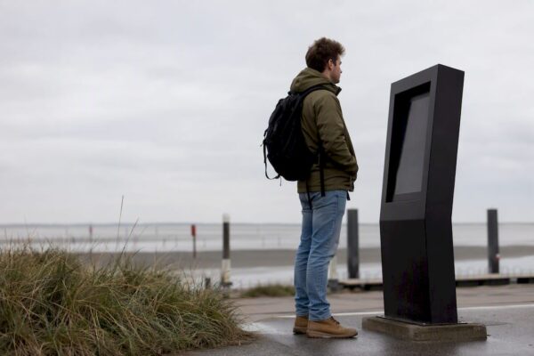 Een reiziger kijkt bij de veerbootterminal op het bord om te zien hoe laat de volgende boot vertrekt.