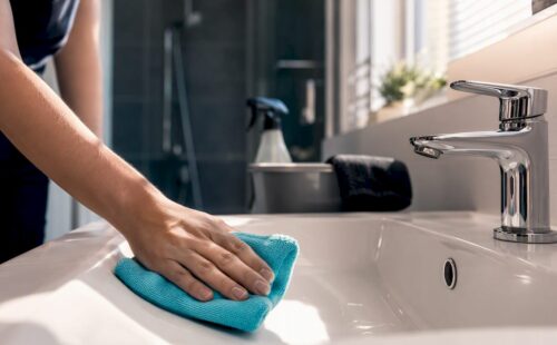 Schoonmaker maakt de wastafel schoon in het vakantiehuis