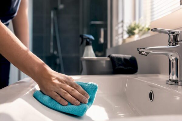 Schoonmaker maakt de wastafel schoon in het vakantiehuis