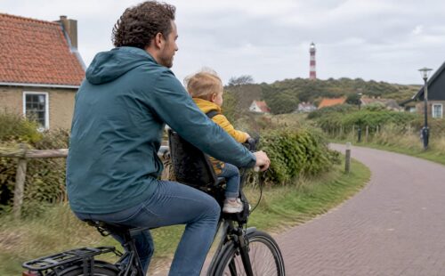 Vader fietst met peuter in een kinderzitje voorop